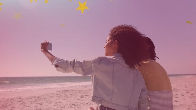 Woman in denim jacket lifting arm framing phone social shot at beach, stars crossing subjects