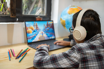 Young man focused on gaming, wearing headphones, using laptop in an indoor setting © JCarlos VBrito