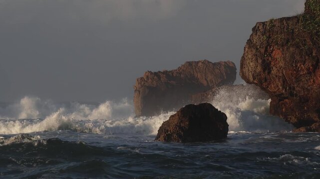 A view of solid coral rocks being hit by waves on a tropical beach.