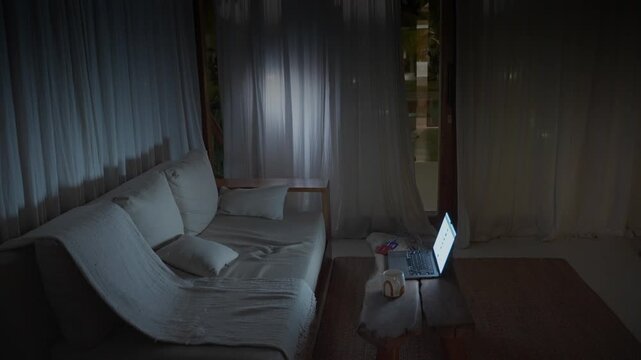 Burglar with flashlight stealing a laptop from a house at night