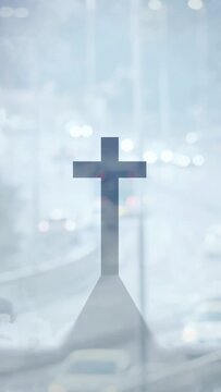 Vertical video: Cars passing sparking haze, lights glaring behind cross standing, creating contrast