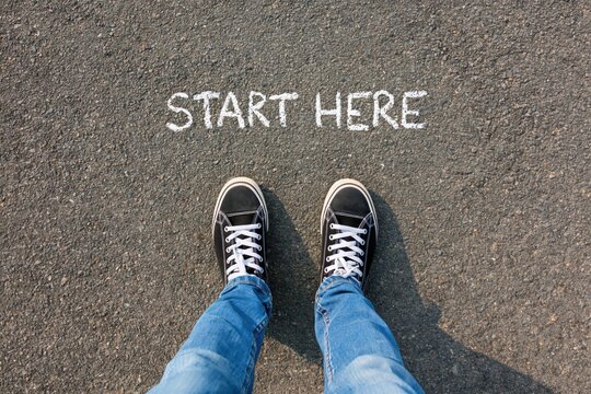 Person standing on start here message on road