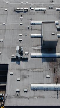 Vertical screen Aerial Industrial Roof Showing Rows Of Vents, Ducts, Skylights And Exhaust Units, Grey Membrane Surface, Service Access Points And Rooftop Mechanical Patterns
