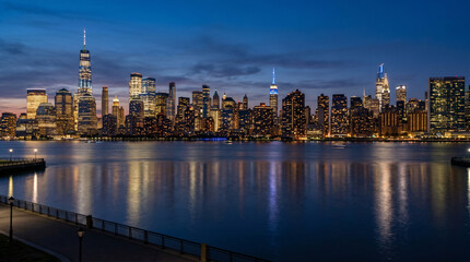 Obraz premium New York City skyline at dusk with illuminated skyscrapers reflecting