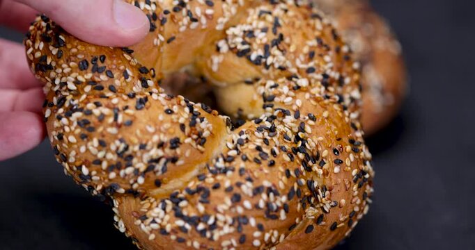 The simit bagel is yellow in sprinkles, the simit bakery product is ring-shaped and lies on the dark stone surface of the table.