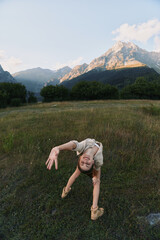 Obraz premium A woman performs a backbend in a grassy field with mountains in the background, capturing a spontaneous outdoor workout moment and a sense of freedom.