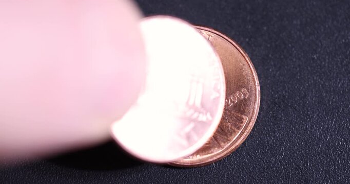   American cent on a black plastic surface while rotating around its axis, an old worn American coin one cent, close up