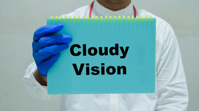 Doctor holds in hands a book with the name of the cloudy vision. Medical concept