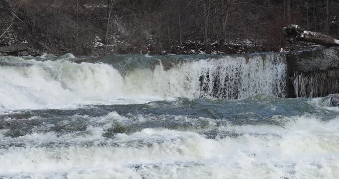 Ithaca, NY, USA - 03-18-2026 Close-up arial, drone, slow motion video of the top of Ithaca Falls, waterfall, with flowing water.	