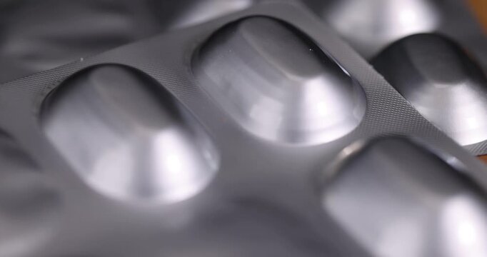Silver foil blister packaging, a medical blister is presented in close-up with an emphasis on the shape of concave pill cells.
