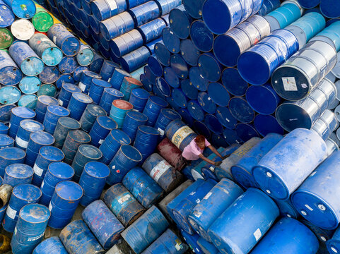 Aerial view of a worker navigating through massive stacks of blue and multi-colored industrial metal drums in a storage yard Dhaka, Dhaka Division, Bangladesh.