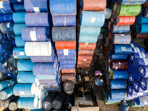 Aerial view of colorful industrial barrels stacked in rows with a worker standing in a narrow alley Dhaka, Dhaka Division, Bangladesh.