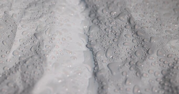wet blue smooth plastic material for wrapping gifts and bouquets, dented in several places, covered with water droplets smooth blue material, water drops