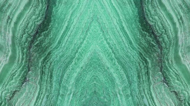 Bright green malachite stone texture with symmetrical wave patterns and vibrant emerald colors for luxury background.