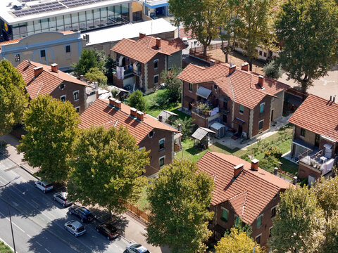 Aerial view of the historic Villaggio Leumann worker houses with red tiled roofs and green trees in Collegno, Piemonte, Italy.