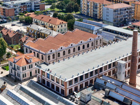 Aerial view of the historic Villaggio Leumann industrial complex with red-tiled roofs and a tall brick chimney in Collegno, Piemonte, Italy.