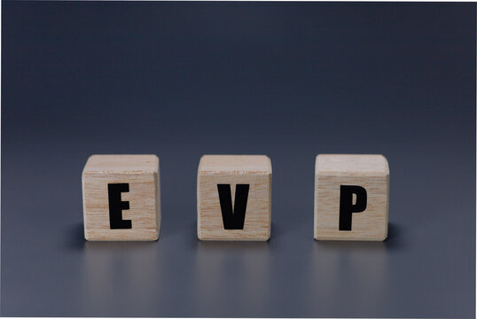 EVP acronym on wooden cubes over a dark grey background. Concept for Employee Value Proposition or Executive Vice President, business leadership, management, and corporate concepts.