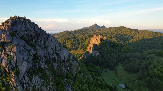 Aerial drone footage of the touristic natural Fatu Nausus peaks site, in South Central Timor, Indonesia, old marmer mining spot, with wild forests around, Mollo mountain peak behind, at golden sunrise