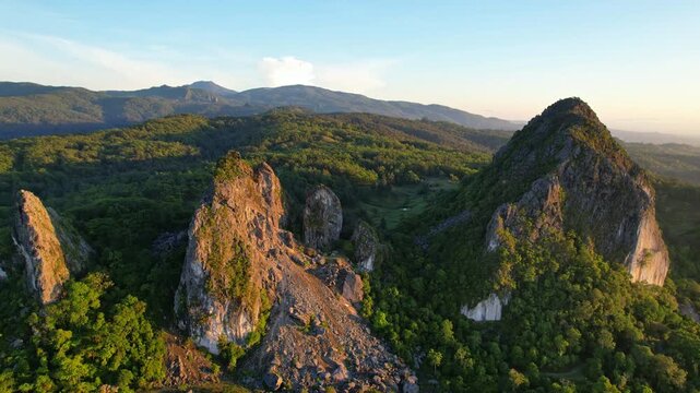 Aerial drone footage of the touristic natural Fatu Nausus peaks site, in South Central Timor, Indonesia, old marmer mining spot, with wild forests around, Mutis park valley behind, at golden sunrise