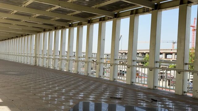 modern covered pedestrian skywalk corridor with metal structure and city view at day