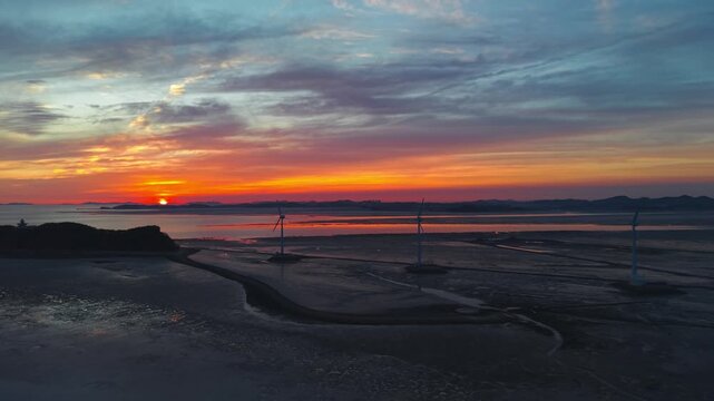 Aerial view of golden sunset at Tando Port sea road featuring iconic wind turbines and Nue Island during low tide in Ansan South Korea