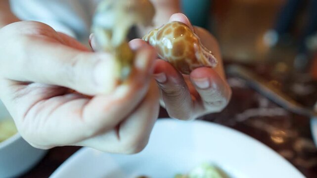 Close Up of Hands Removing a Snail from its Shell at a Buffet