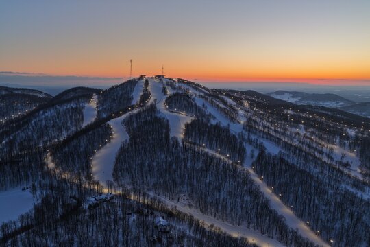 Aerial drone view of illuminated Bromont ski resort slopes at dusk, Quebec, Canada in winter. g.