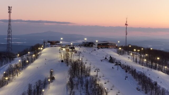 Aerial drone view of illuminated Bromont ski resort slopes at dusk, Quebec, Canada in winter. g.