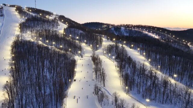 Aerial drone view of illuminated Bromont ski resort slopes at dusk, Quebec, Canada in winter. g.