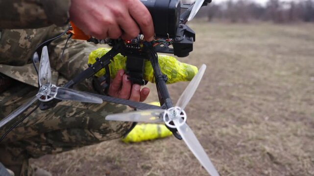 Close of Ukrainian soldier launching FPV drone with visible propellers and tactical gear outdoors