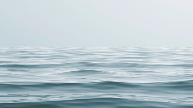 Calm ocean waves gently ripple under a soft, overcast sky, creating a peaceful and serene seascape.