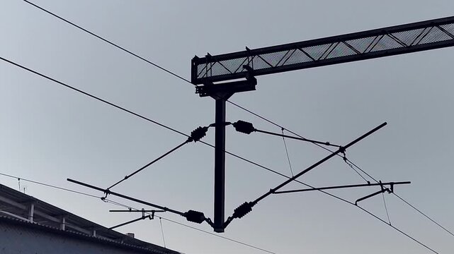 Close handheld view of railway overhead electric catenary system and wires. Ideal for transport infrastructure, electrification, engineering, and industrial visuals.