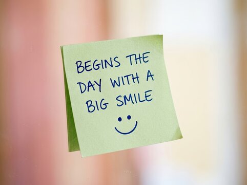 Yellow sticky note with handwritten positive message and smiling face icon, blurred neutral backdrop, inspirational, motivational Concept