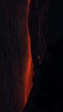Vertical Screen: Yosemite National Park Firefall phenomenon with glowing orange waterfall cascading down dark granite cliff face at sunset creating dramatic natural light display