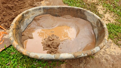 Fototapeta premium Cement Mixing in Basin, Construction Work with Sand and Water. Mixing Concrete in Plastic Tub, Building Construction Process Close Up