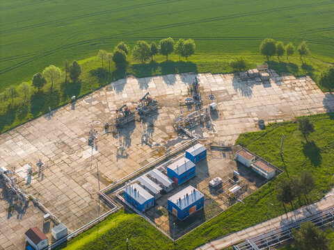 Aerial view of the UGS Damborice facility featuring oil pump jacks and blue industrial buildings surrounded by lush green fields and trees Damborice, South Moravian Region, Czechia.
