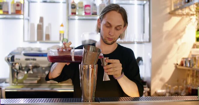 Cafe drink. Using jigger. Bartender pouring alcohol liquid from liquor bottle to metal shaker. Measuring syrup for refreshing cocktail.