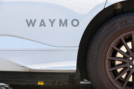 Waymo autonomous vehicle exterior with branding on the passenger door, representing self driving technology, automated transportation, and advanced mobility systems