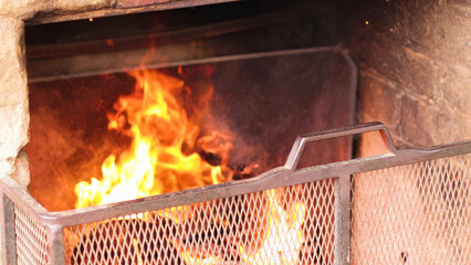 Obraz premium Bright Orange Flames Burning Behind a Metal Fireplace Safety Screen