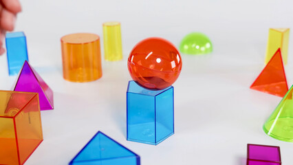 Red Sphere Balanced on Blue Hexagonal Prism with Other Geometric Shapes © blueringmedia