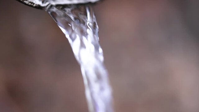 A strong stream of water flows from a drainpipe close-up