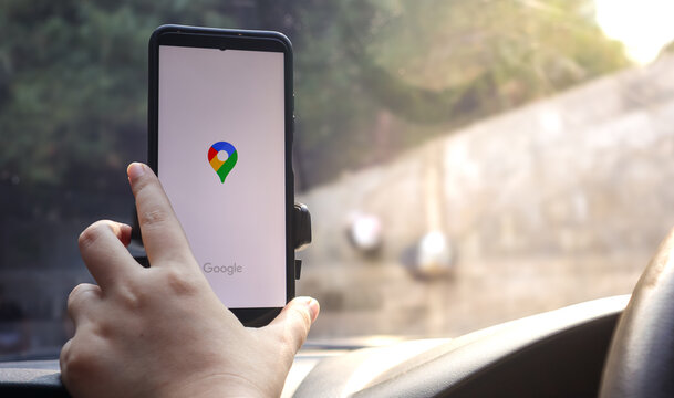 Female driver opening Google Maps on smartphone mounted inside car dashboard for GPS navigation, route directions and travel assistance while driving. Depok, Indonesia 11 May 2026.