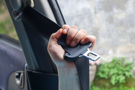 Close up of hand pulling car seat belt before driving inside vehicle, road safety and transportation protection concept in modern car interior.