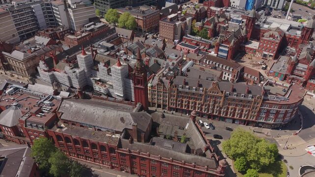 Cinematic drone footage above historic Victorian red brick buildings and old architecture in Birmingham city centre, England with detailed urban landscape and city streets.