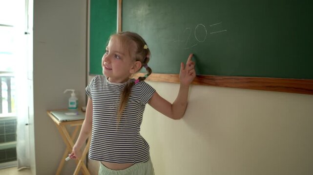 Young students are calculating the result of numbers to write the answer on the blackboard at the front of the classroom. This is a math activity for elementary school classrooms
