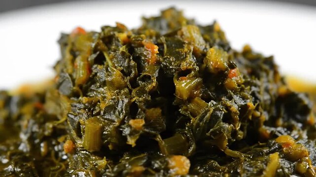 Delicious Close-Up of Stewed Leafy Green Vegetables, Likely Collard Greens or Spinach, Served Hot on a White Plate. A Healthy and Traditional Side Dish.