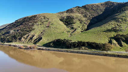 Naklejka premium Aerial View of Green Hills and Murky Water in Akaroa New Zealand
