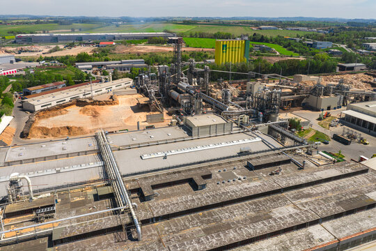 Aerial view of a large industrial wood processing plant with complex piping systems, silos, and storage areas Jihlava, Vysocina Region, Czechia.
