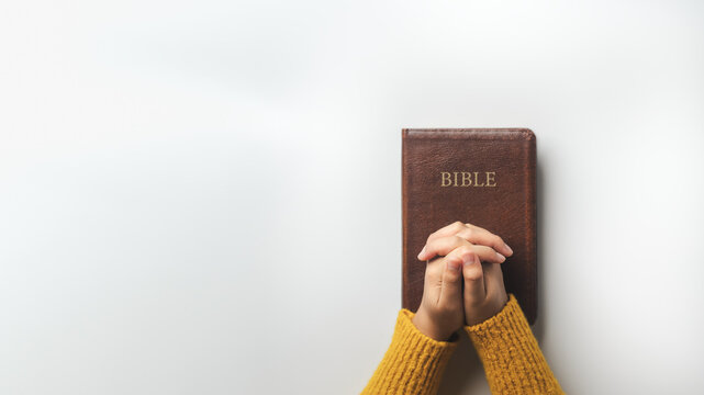 Hands clasped in prayer to God over a bible. Bible study concept. Praise or hope. Christian faith. Spirituality and religion. Background copy space.