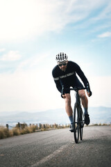 Naklejka premium Fitness, cycling or man on road with practice, endurance training or challenge in cardio workout. Serious, sky space or cyclist outdoor with bike, physical activity or riding progress in sports hobby